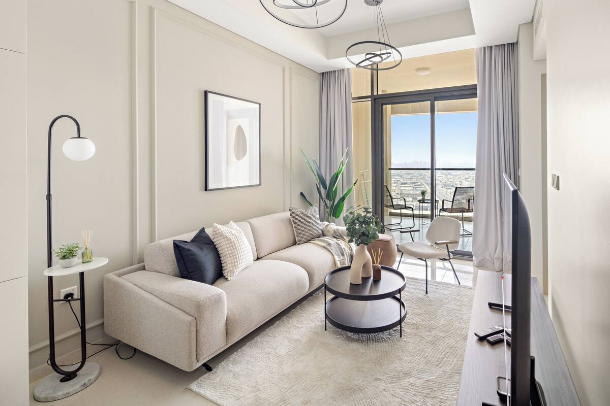 A modern living room with a sofa, a round coffee table, a floor lamp, and a TV.