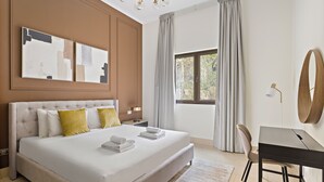 Una habitación de hotel moderna con una cama grande, un escritorio y vistas a zonas verdes.