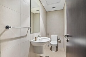 A modern bathroom with a sink, mirror, and toilet. - Silkhaus Marina Rise Towers (Abu Dhabi)