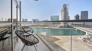 A balcony with glass railings, a view of a cityscape, and a river. - Silkhaus Marina Rise Towers (Abu Dhabi)