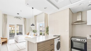 A modern kitchen with a built-in washing machine, an oven, and a large island. - Silkhaus Marina Rise Towers (Abu Dhabi)