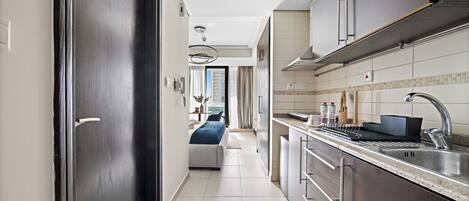 A modern kitchen with a built-in oven, stainless steel sink, and a dining area with a table and chairs.