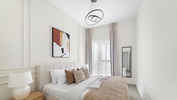 A modern bedroom with a bed, bedside table, lamp, and a large window with curtains. - Silkhaus Golfville (Dubai)