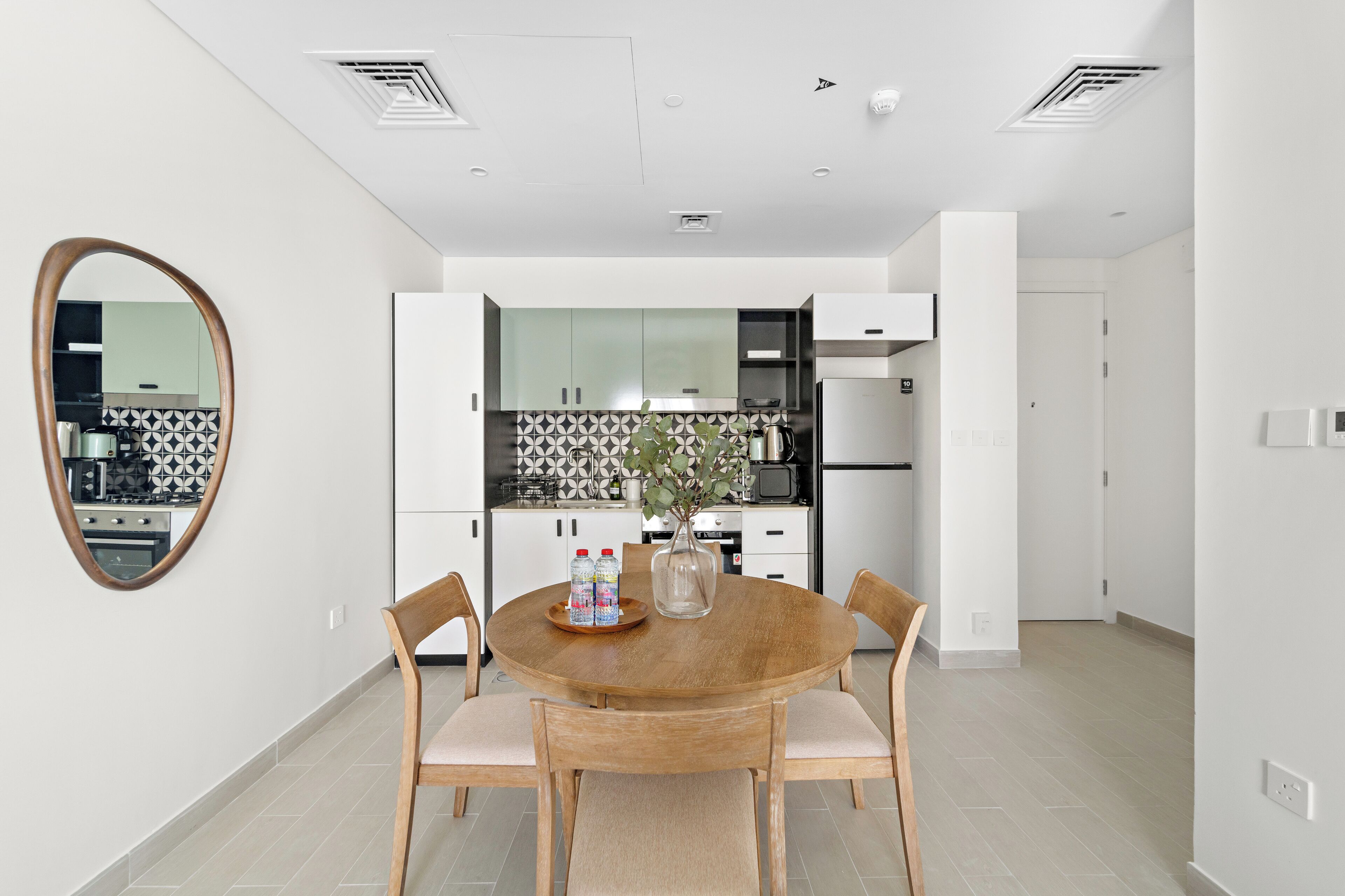 A modern kitchen with white cabinets, a stainless steel refrigerator, and a patterned backsplash.