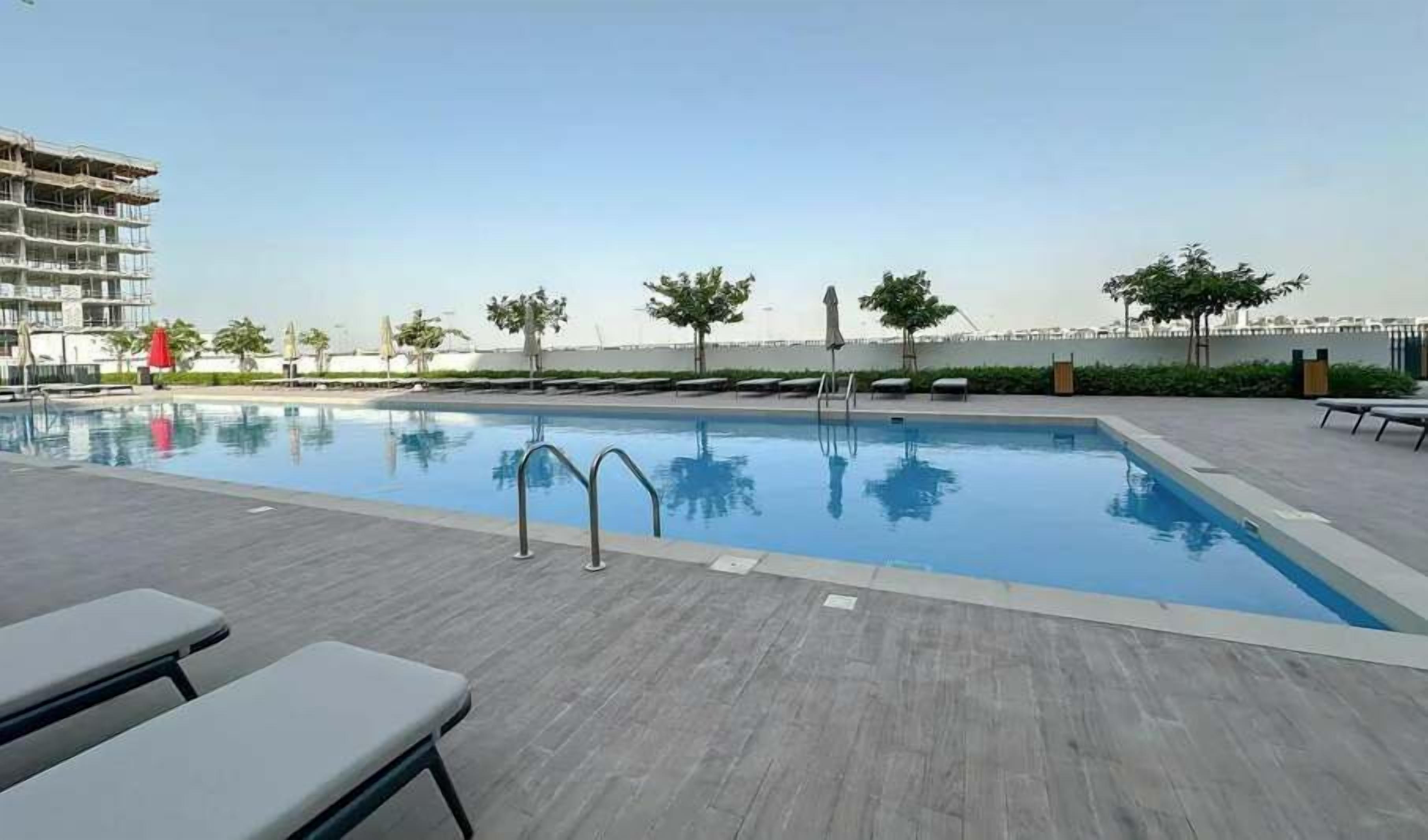 A swimming pool with lounge chairs and a view of a building in the background.