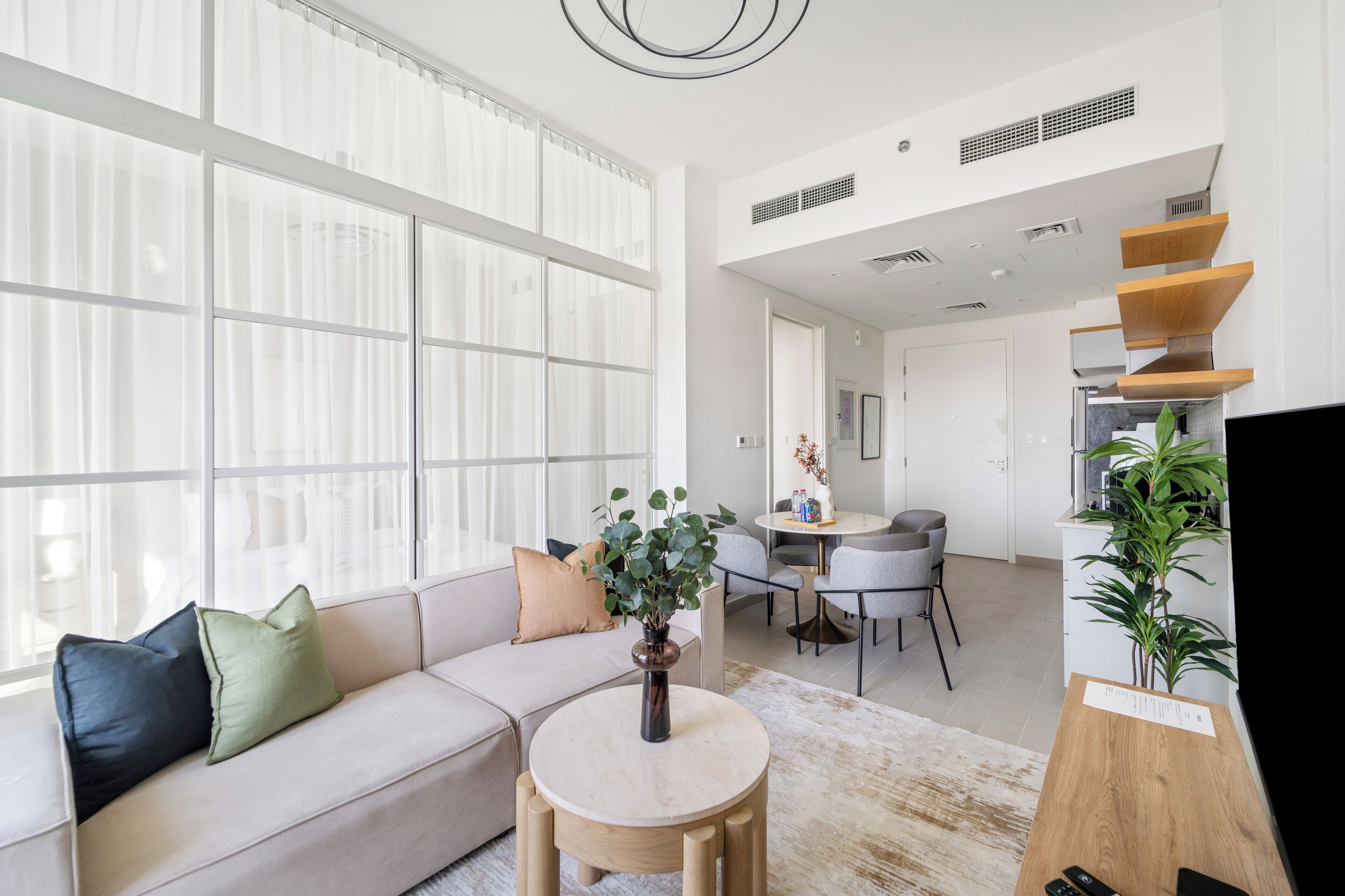 Una sala moderna con un sofá, una mesa redonda de madera y una planta en maceta.