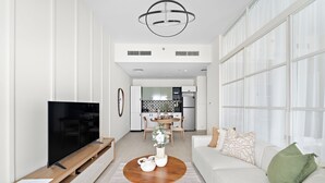 A modern living room with a flat-screen TV, wooden coffee table, and a sofa with decorative pillows. - Silkhaus Golfville (Dubai)