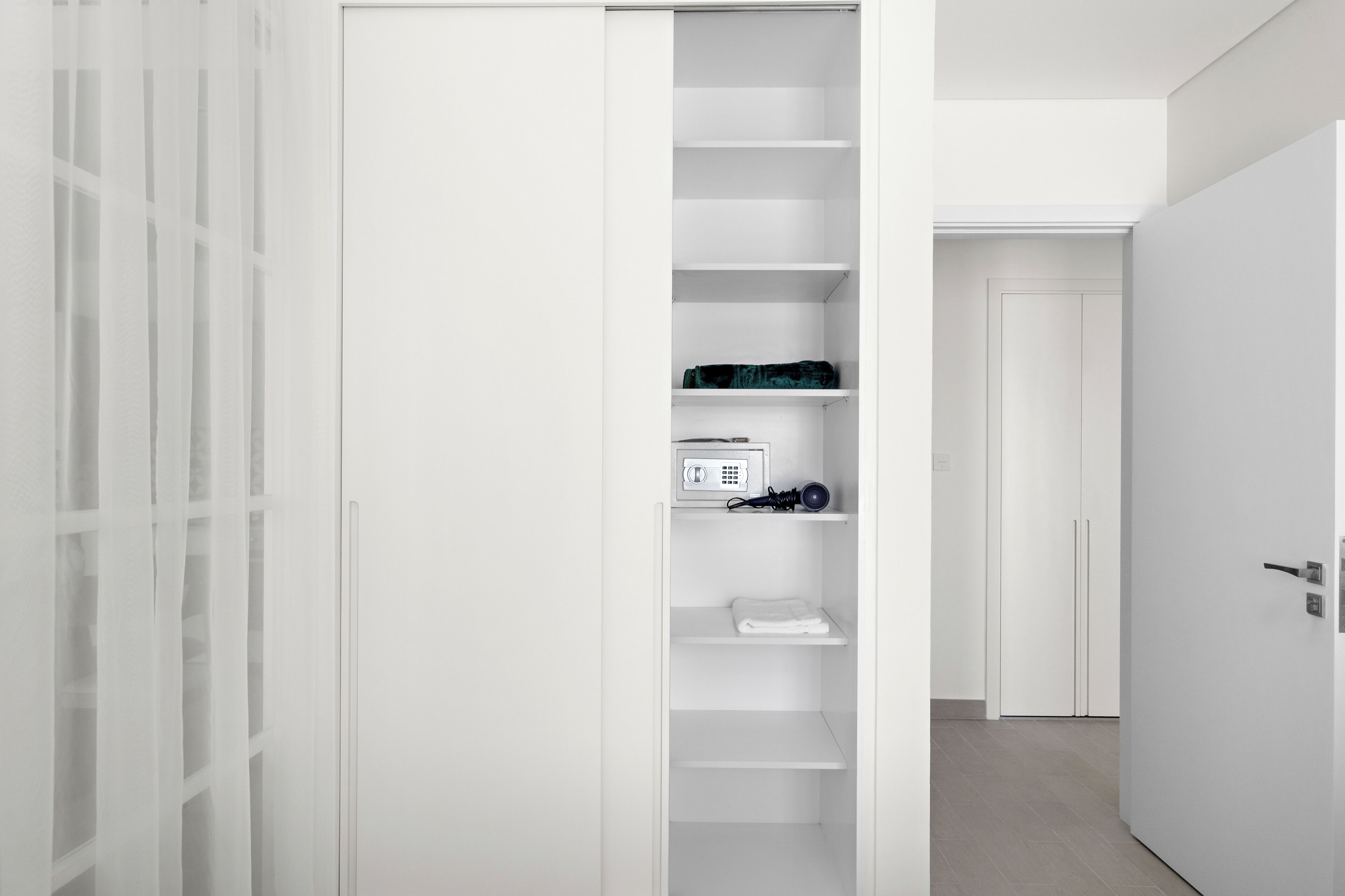 A white walk-in closet with shelves and a door.