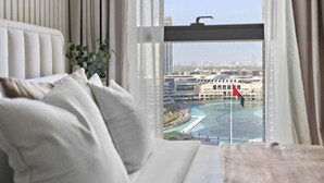 A modern hotel room with a large window offering a view of a cityscape and a swimming pool. - Silkhaus Act One Towers (Dubai)