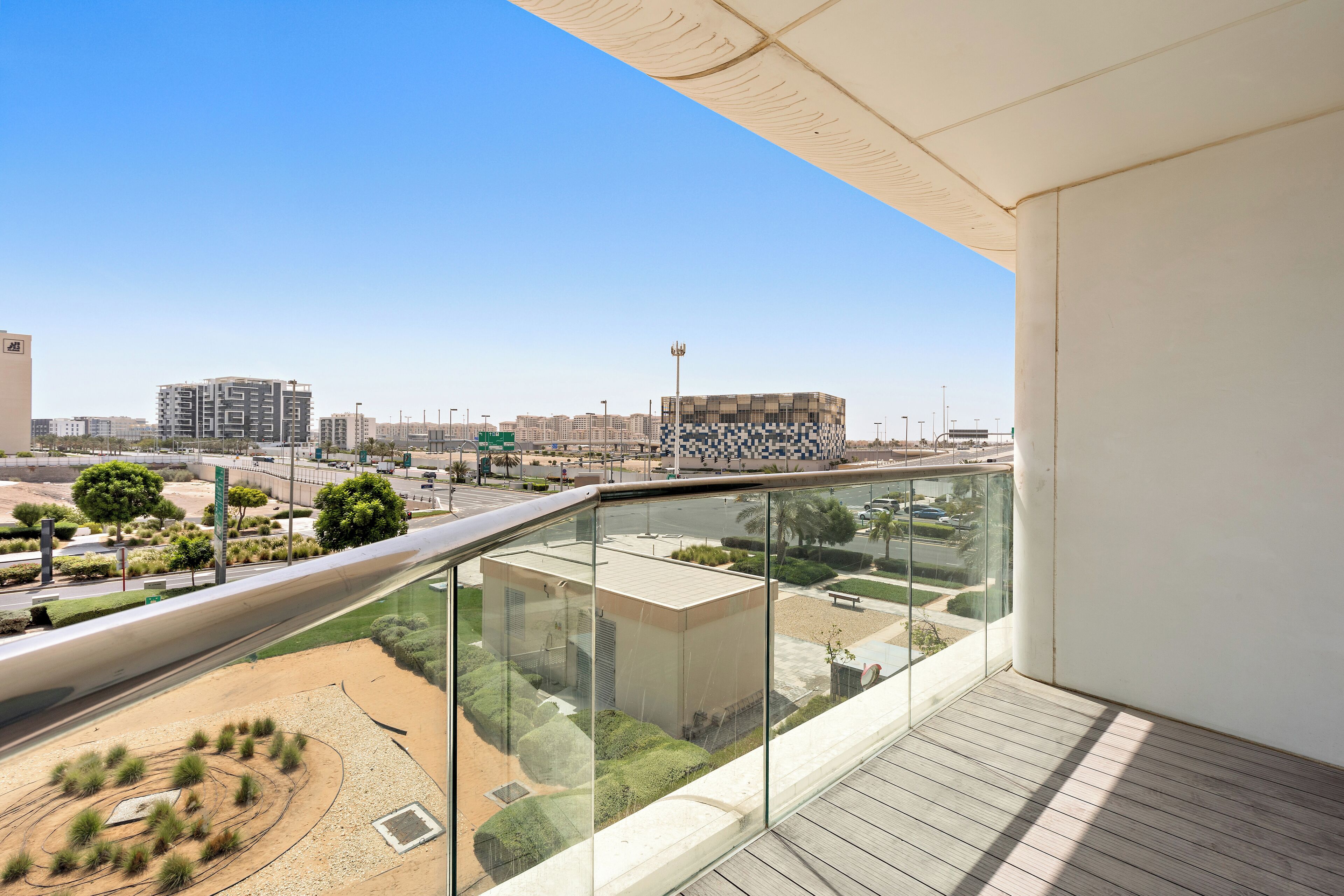 A modern apartment with a balcony overlooking a landscaped area and a cityscape.