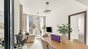 Un salon moderne avec une table à manger en bois, des canapés beiges et une grande fenêtre.