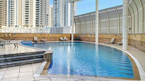 Une piscine avec des marches permettant d’y accéder, entourée d’immeubles de grande hauteur.