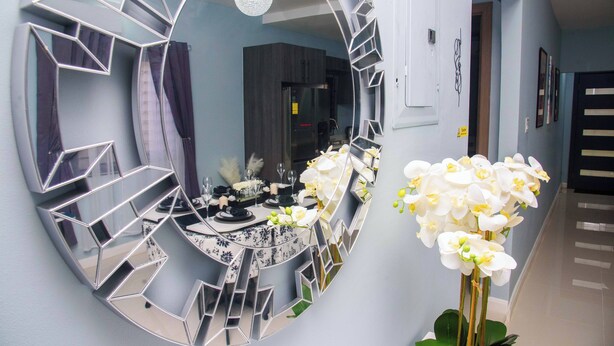 A hallway with a large heart-shaped mirror reflecting a dining area, a door, and a staircase. - Modern, spacious 2 bed, 2 bath villa, sleeps 6 - centrally in located Ocho Rios. (Ocho Rios)