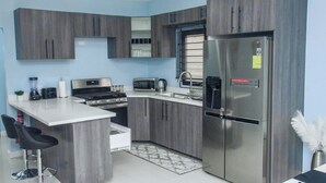 A modern kitchen with grey cabinets, a stainless steel refrigerator, a microwave, and a gas stove. - Modern, spacious 2 bed, 2 bath villa, sleeps 6 - centrally in located Ocho Rios. (Ocho Rios)