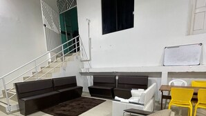 A modern living room with a sofa, a coffee table, and a TV stand. There is a staircase with a railing and a window above it. - Pousada Torre Forte (Rio Branco)