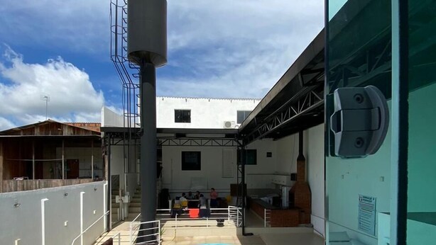 A pool area with a clear blue pool, a metal staircase, and a white building in the background. - Pousada Torre Forte (Rio Branco)