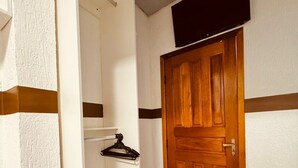 A hallway with a wooden door, a coat rack, and a white wall with a brown stripe. - Pousada Torre Forte (Rio Branco)