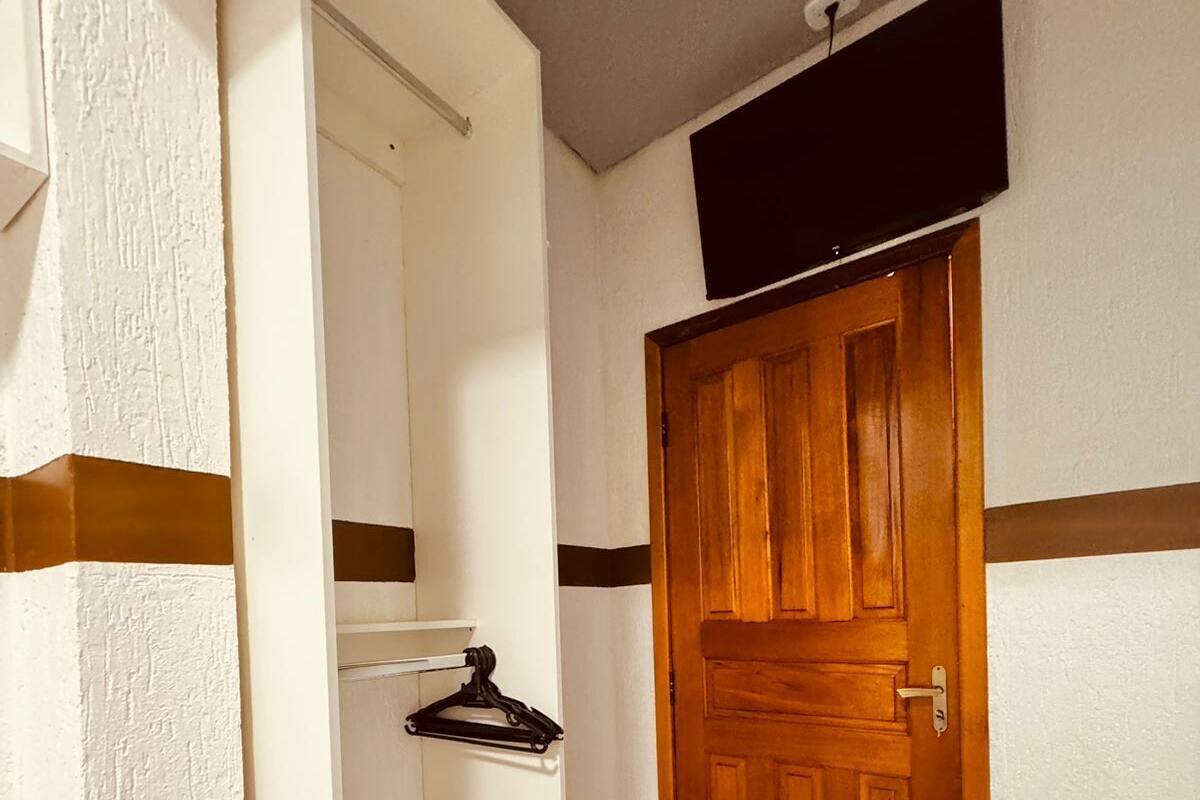 A hallway with a wooden door, a coat rack, and a white wall with a brown stripe.