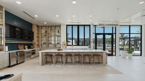 A modern kitchen with a central island, bar stools, and large windows offering a view of the city. - VIEWS! Capitol! Year round POOL/Spa/Gym/Bowling! (Salt Lake City)