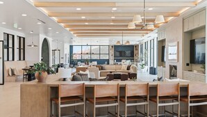 A spacious, well-lit interior with a central seating area, a kitchen, and large windows offering a view. - VIEWS! Capitol! Year round POOL/Spa/Gym/Bowling! (Salt Lake City)