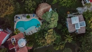 An aerial view of a property with a swimming pool, a large tree, and several buildings.