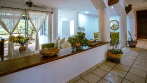 A spacious room with a long wooden counter, potted plants, and a view of the outdoors.