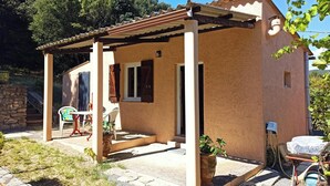 Ein kleines, eingeschossiges Gebäude mit Ziegeldach und einer überdachten Terrasse.