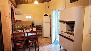Eine kompakte Küche mit Holzschränken, einem Esstisch mit Stühlen, einem Kühlschrank und einer Mikrowelle.