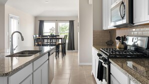 Een moderne keuken met een groot eiland, een inbouwoven en roestvrijstalen apparatuur.