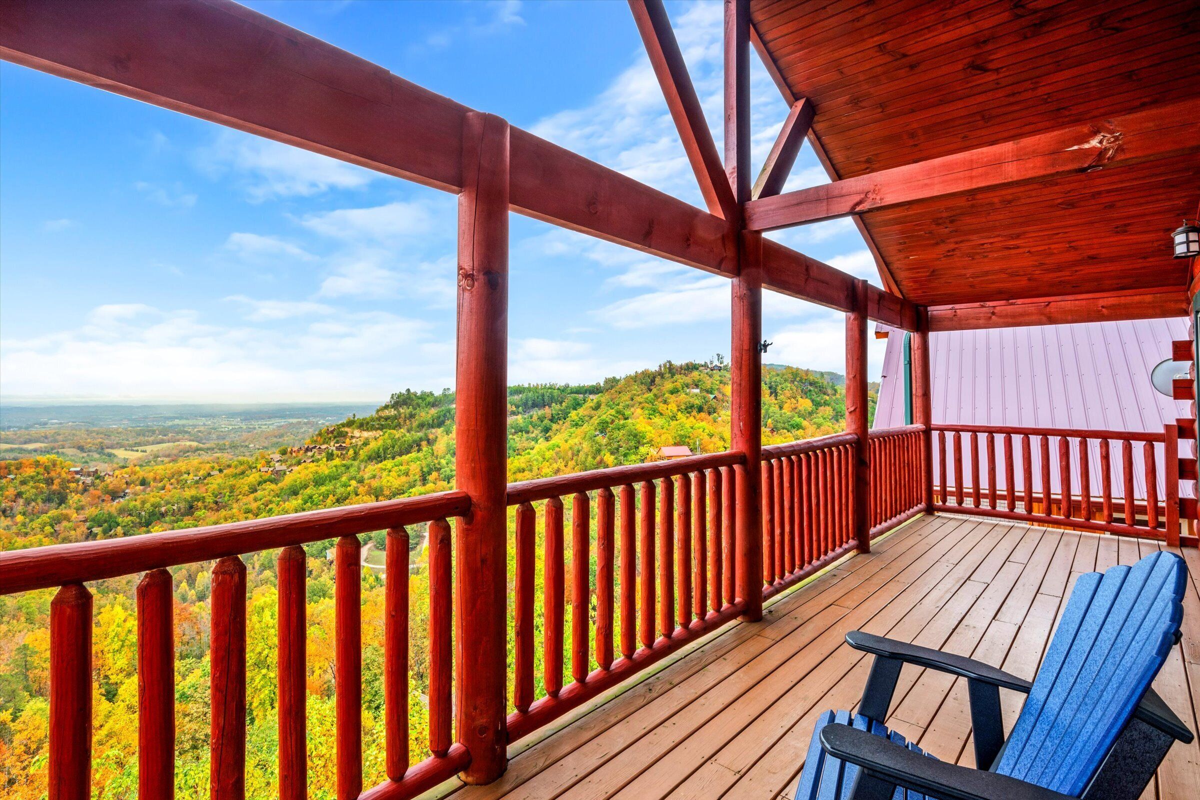 A wooden deck with a red railing overlooking a scenic landscape.
