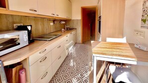 Una cocina compacta con microondas, cafetera y una pequeña mesa.
