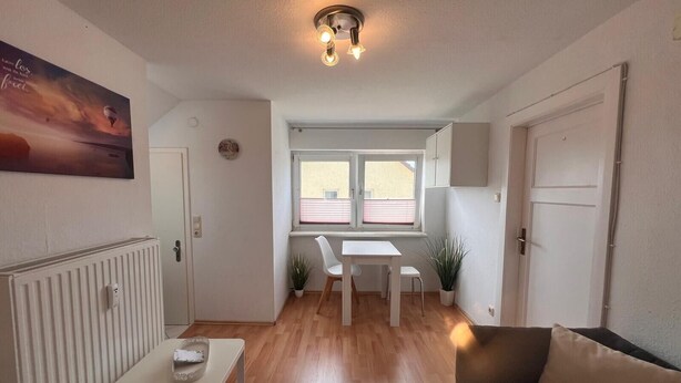 Een moderne woonkamer met een bank, een eettafel en een keuken op de achtergrond.