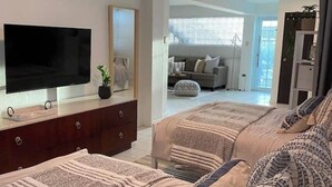 Un dormitori modern amb un llit gran, televisió i vistes a la zona d'estar.
