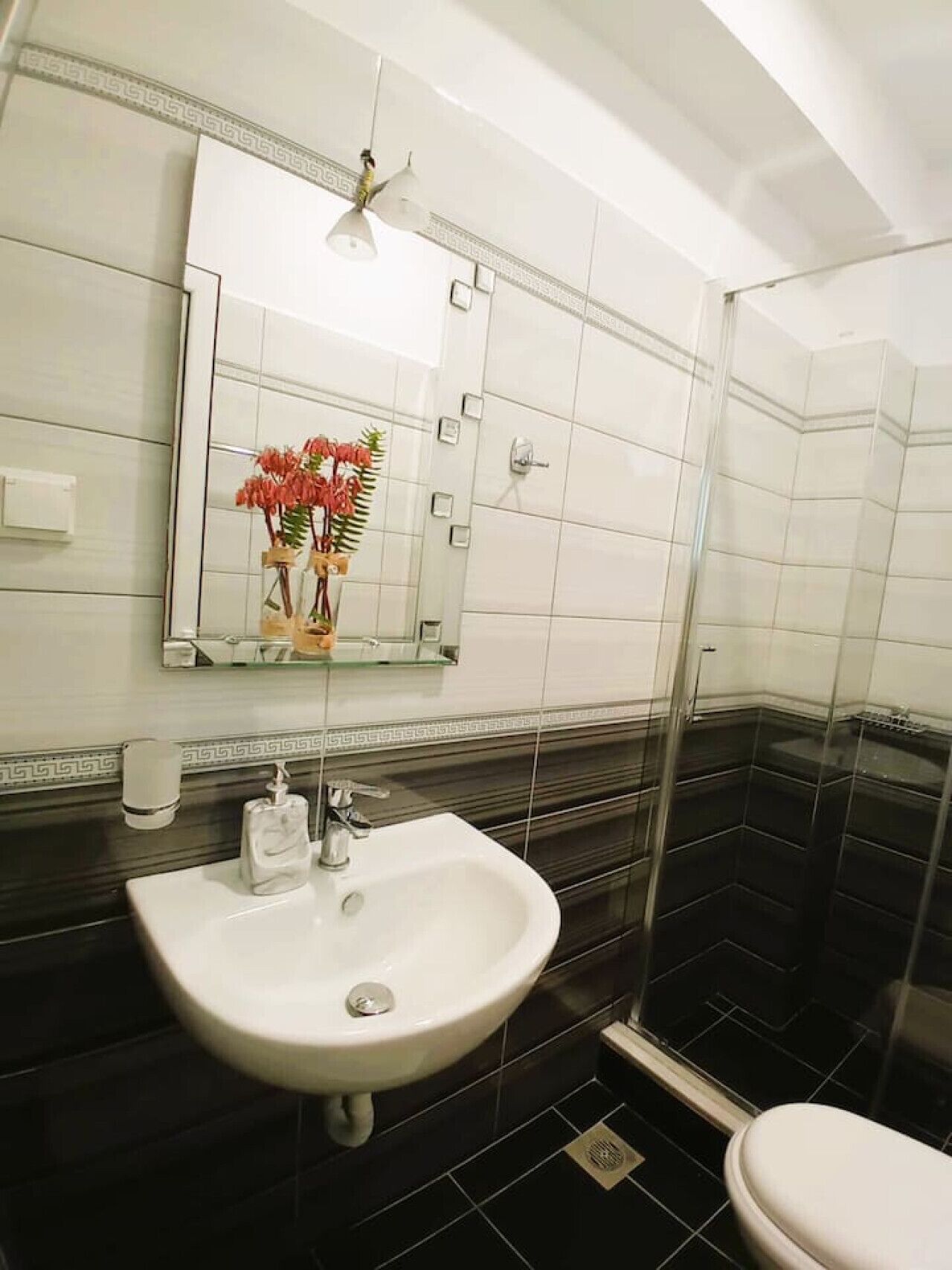 Ein Badezimmer mit Waschbecken, Spiegel und Duschbereich.