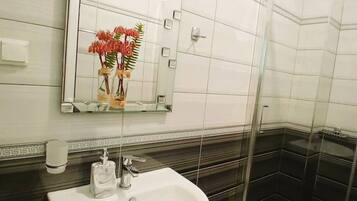 Ein Badezimmer mit Waschbecken, Spiegel und Duschbereich.