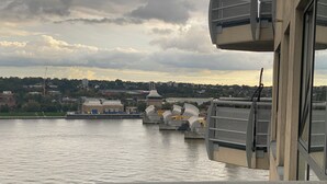 A view from a boat with a docked ship in the background, a bridge, and buildings across the water. - Cosy 2 Bedroom Royal Docks Apartment (London)