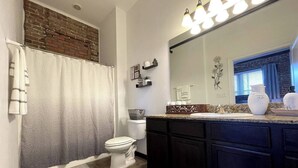 Une salle de bain équipée d’une douche, de toilettes, d’un meuble-lavabo avec un miroir et d’un évier.