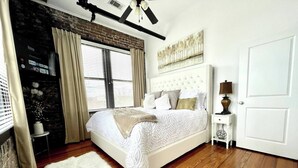 Une chambre avec un grand lit, une porte blanche, une petite table de chevet et un élément décoratif mural.