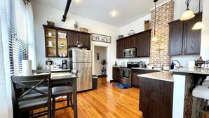 Une cuisine moderne avec des meubles en bois foncé, des appareils électroménagers en acier inoxydable et un mur décoratif en briques.