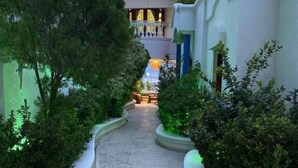 A pathway flanked by neatly trimmed bushes, leading to a building with a balcony. - Azul Hotel Boutique (Santa Marta)