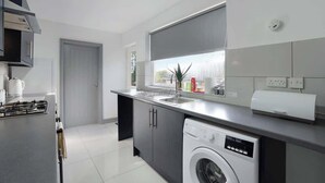 A modern kitchen with a washing machine, a stove, and a window with a view. - Comfortable 2BR Home 10 Min to Durham Cathedral (Ushaw Moor)