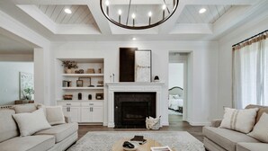 Una sala de estar con chimenea, sofás, una mesa de centro y una estantería.