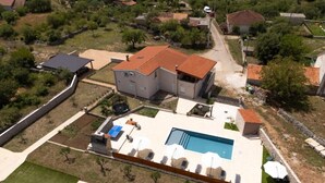 A residential property with a swimming pool, a covered patio, and a fenced yard.