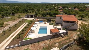 A villa with a swimming pool, a tennis court, and a view of the surrounding countryside.