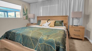 A bedroom with a large bed, two bedside tables, a ceiling fan, and a window with curtains. - Pool + Ping Pong | Pets OK | Bonita Beach (Bonita Springs)