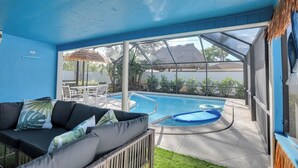 A pool area with a covered seating area and a thatched roof structure. - Pool + Ping Pong | Pets OK | Bonita Beach (Bonita Springs)