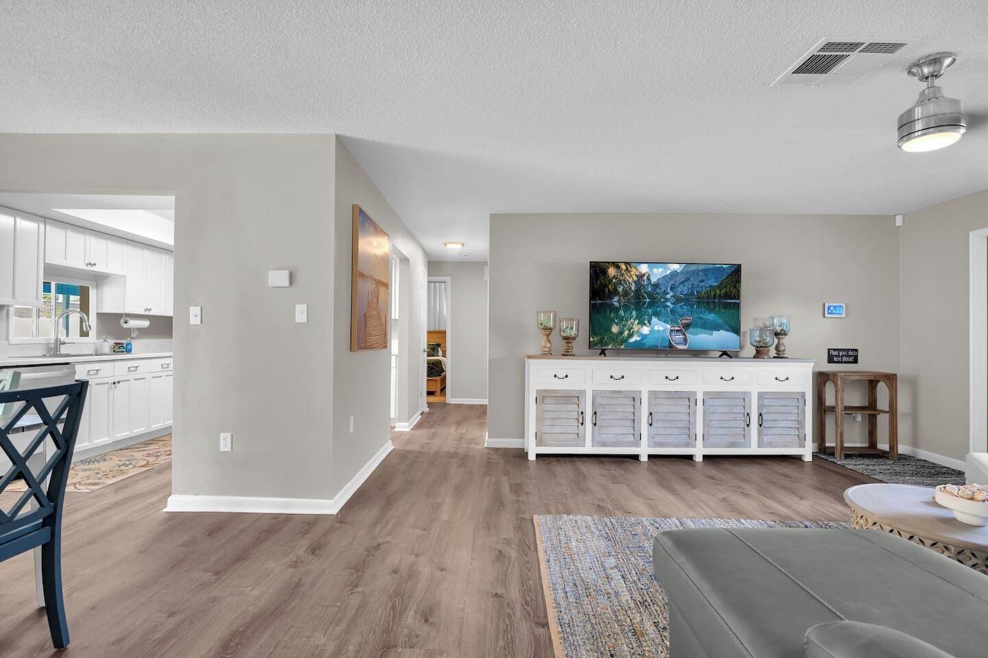 A modern living room with a flat-screen TV, a white console table, and a grey sofa.