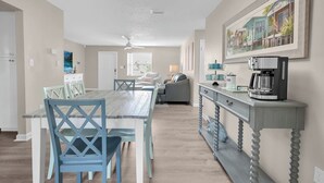 A spacious kitchen with a dining area, featuring a wooden table, blue chairs, and a coffee station. - Pool + Ping Pong | Pets OK | Bonita Beach (Bonita Springs)