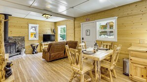 A wooden cabin interior with a fireplace, sofa, dining table, and chairs. - Walk to Water: Cozy Cabin in Green Valley Lake! (Green Valley Lake)