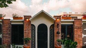 Un edificio de fachada de ladrillo, con una entrada central en arco y plantas en macetas.